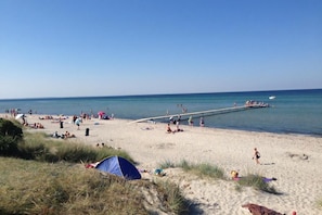 A beach with a pier, tents, and people.
