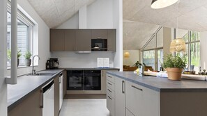 A modern kitchen with integrated appliances, a large island, and a view of the outdoors.