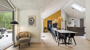 Un comedor moderno con una mesa larga, sillas, iluminación colgante y vistas al exterior.
