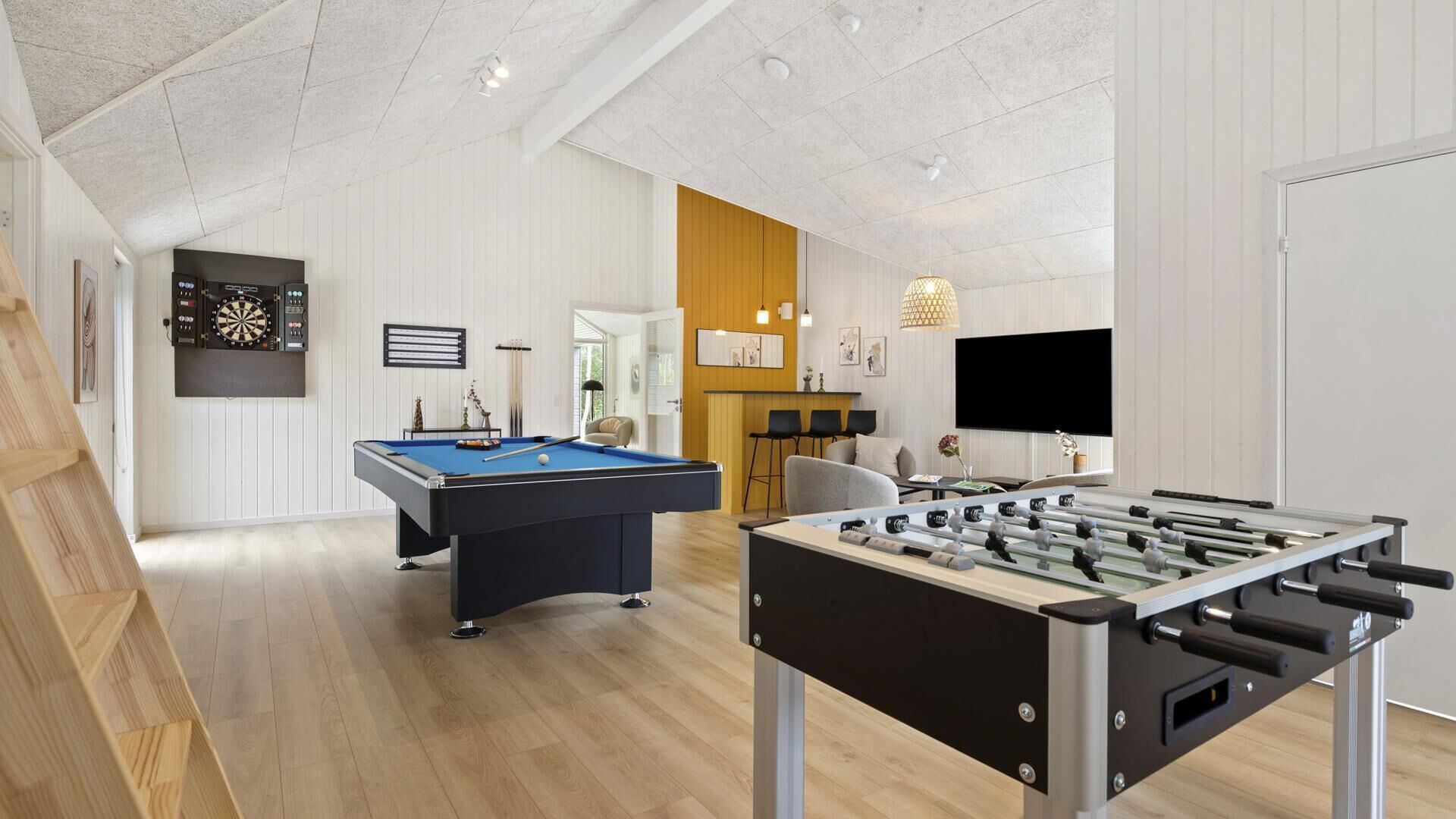 Ett modernt, inomhusutrymme för rekreation med ett biljardbord, ett fotbollsspel och en darttavla.