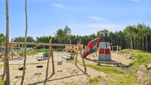 Un parque infantil con columpios, toboganes y una estructura para escalar.