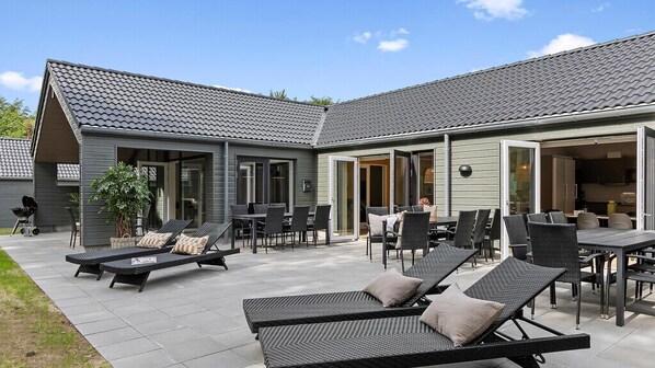 A modern house with a patio area featuring outdoor furniture and a grill.