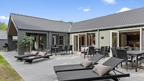 A modern house with a patio area featuring outdoor furniture and a grill.