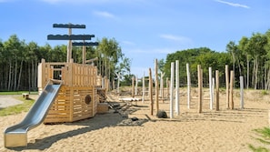 A playground with a slide, climbing structures, and a sandy area.