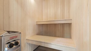 A sauna with a Harvia Vega sauna heater, a wooden bench, and a sloped ceiling. - VillaVilla 832 - Fjellerup, Østjylland (Glesborg)