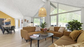 A modern living room with a sectional sofa, a coffee table, and a large window offering a view of the outdoors.