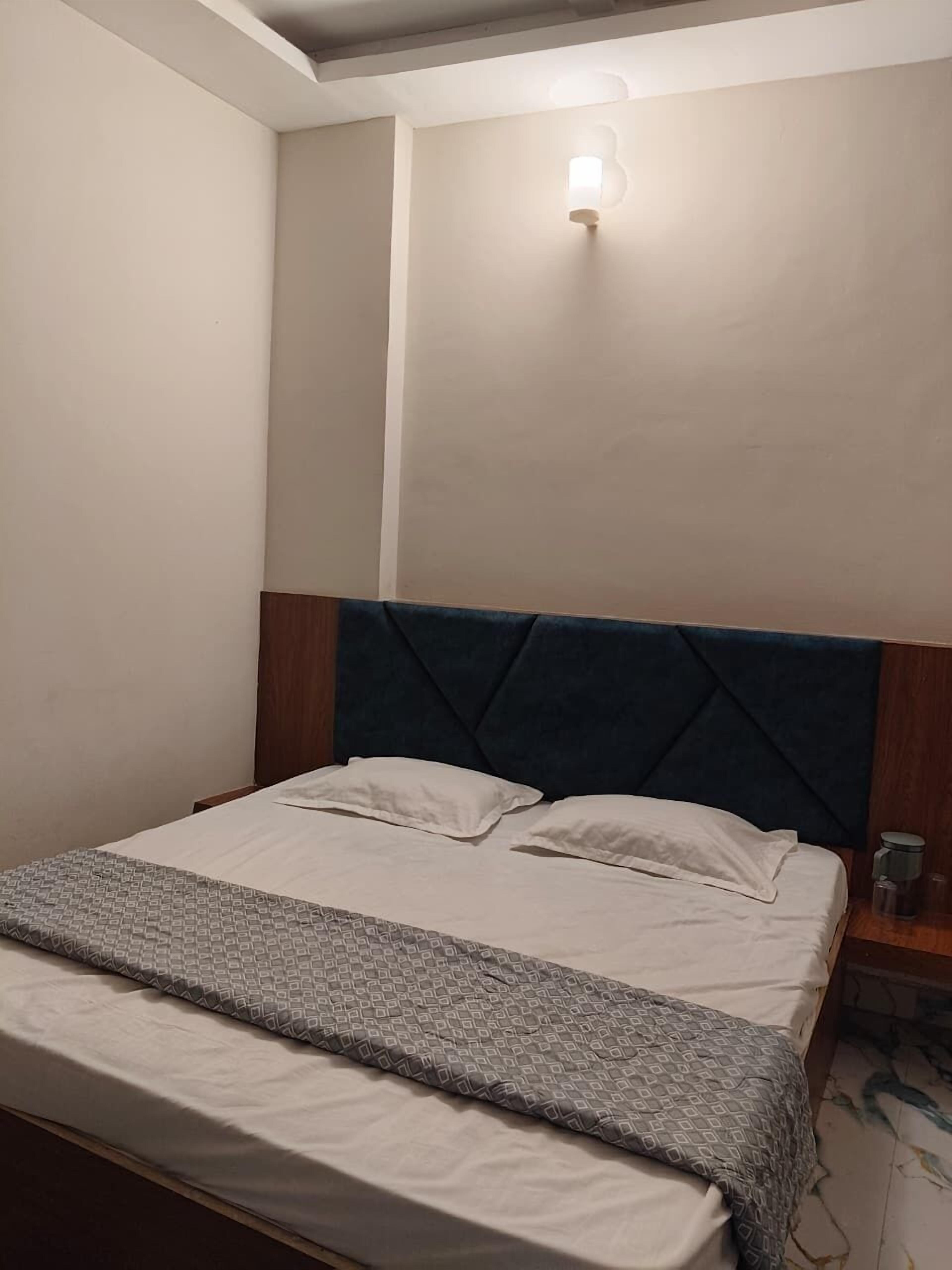 A bedroom with a bed, a headboard, a bedside table, and a wall-mounted light fixture.