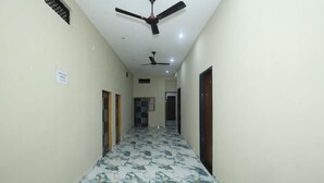 A hallway with a ceiling fan, a sign on the wall, and a patterned floor. - Shri Bala ji Dham (Mathura)