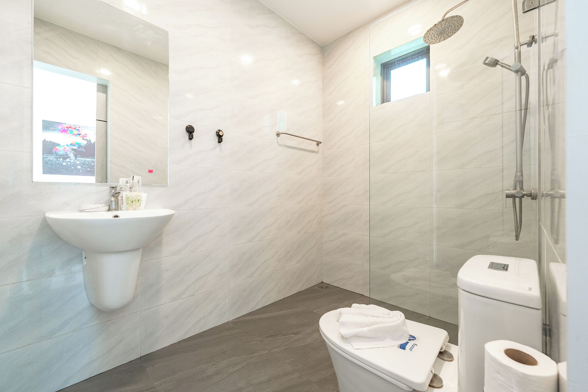 A modern bathroom with a sink, toilet, and shower.