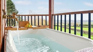 A hot tub with a view of a green landscape.