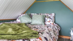 Ein raumförmiger Raum mit einem Bett, grünen Kissen und einer grünen Decke.