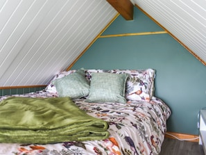 Ein raumförmiger Raum mit einem Bett, grünen Kissen und einer grünen Decke.