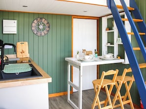 Cocina pequeña con mostrador de madera, un reloj y una escalera.