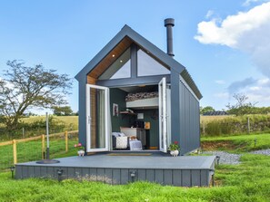 Eine moderne, eingeschossige Holzhütte mit großzügigem Eingangsbereich, sichtbarer Küche und einer Terrasse.
