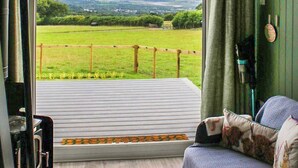 Ein Zimmer mit Blick auf ein grünes Feld und eine entfernte Landschaft.