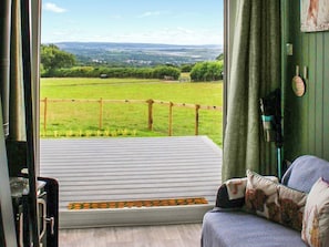 Ein Zimmer mit Blick auf ein grünes Feld und eine entfernte Landschaft.
