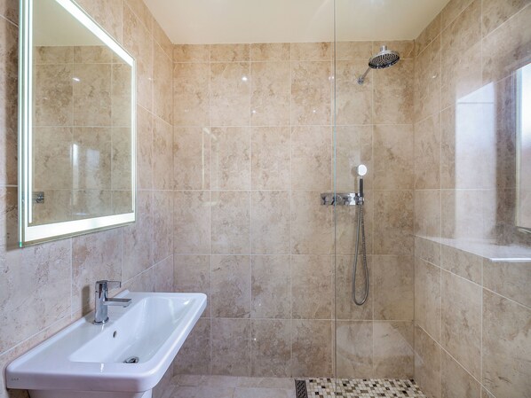 Une salle de bain avec une douche, un lavabo et un miroir.