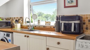 A kitchen with a sink, a microwave, a toaster, and a washing machine.
