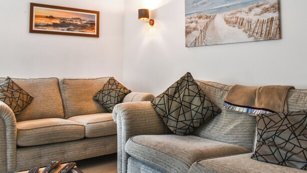 A living room with two sofas, a wall-mounted light, and two framed pictures.