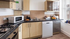 Een moderne keuken met houten kastjes, een magnetron, een vaatwasser en een spoelbak.