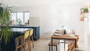 A modern kitchen with a central island, dining area with chairs, and a window. - 4 bedroom accommodation in St Agnes (St Agnes)