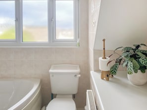 A bathroom with a toilet, a bathtub, and a window.