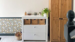 A room with a white dresser, wicker baskets, a potted plant, and a wooden cabinet. - 4 bedroom accommodation in St Agnes (St Agnes)
