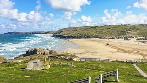 A coastal landscape with a beach, grassy areas, and rocky outcrops. - 4 bedroom accommodation in St Agnes (St Agnes)