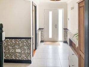 Un pasillo con un papel tapiz decorativo, una puerta al final y un armario de madera a la derecha.