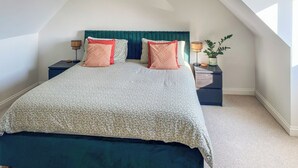 A bedroom with a bed, two nightstands, a lamp, and a potted plant. - 4 bedroom accommodation in St Agnes (St Agnes)
