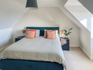 A bedroom with a bed, two nightstands, a lamp, and a potted plant.