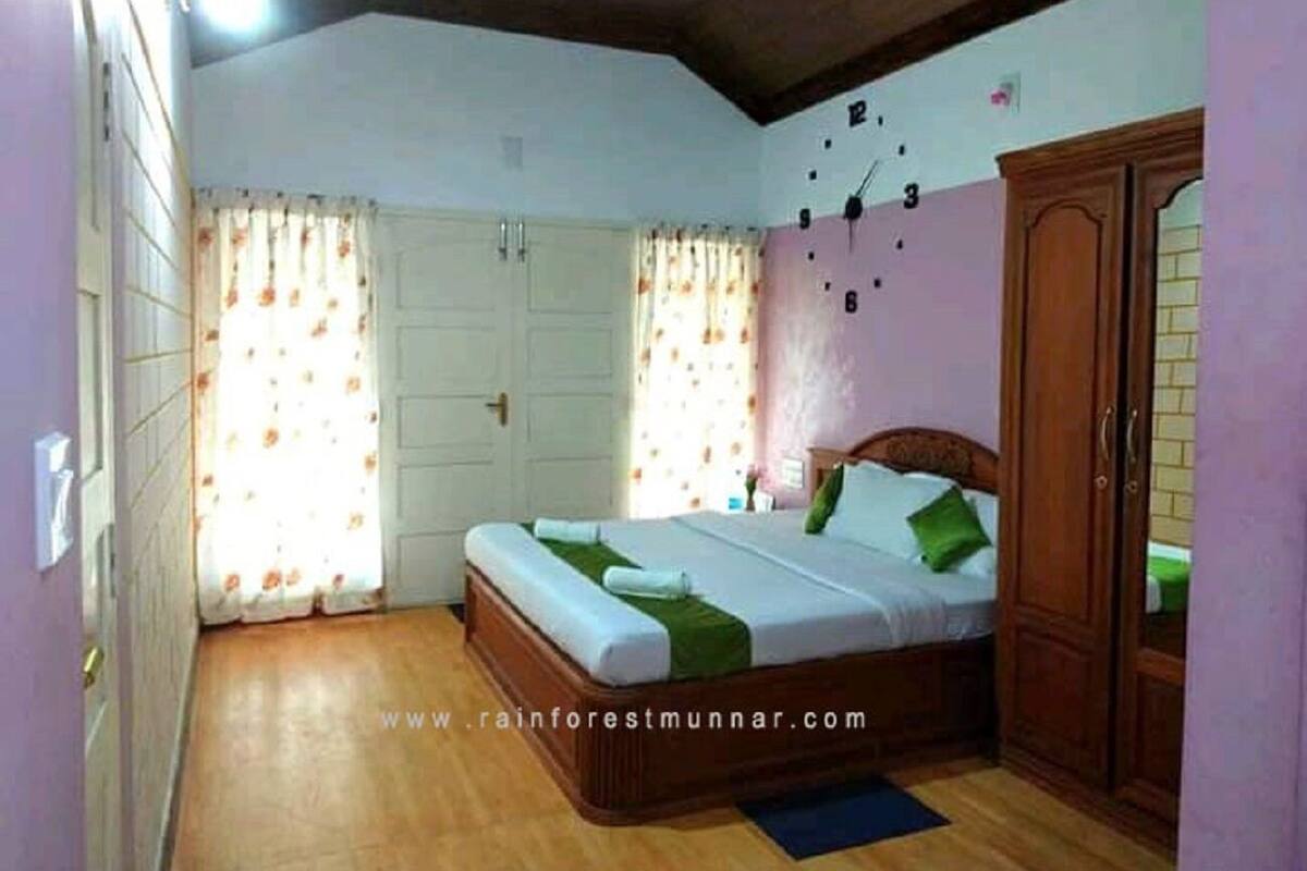 Un dormitorio con cama, cortinas, un armario y suelo de madera.