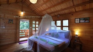 Une chambre dans une cabane en bois, avec un lit à baldaquin, un plafond en bois et une fenêtre donnant sur un paysage verdoyant.