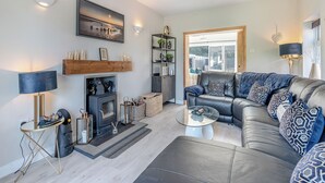 A modern living room with a fireplace, leather sofa, and a glass coffee table. - 2 bedroom accommodation in Chapel St Leonards, near Skegness (Chapel St Leonards, near Skegness)