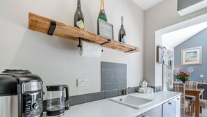 A modern kitchen with a coffee maker, a kettle, and a wine bottle on a wooden shelf. - 2 bedroom accommodation in Chapel St Leonards, near Skegness (Chapel St Leonards, near Skegness)