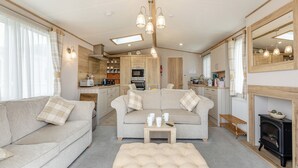 A cozy living room with a sofa, ottoman, and a fireplace. - 3 bedroom accommodation in Weymouth (Weymouth)