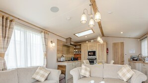 A cozy living area with sofas, a coffee table, and a kitchen in the background. - 3 bedroom accommodation in Weymouth (Weymouth)
