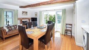 A dining area with a wooden table set for six, surrounded by chairs. A sofa and a chair are visible in the background. - 3 bedroom accommodation in Coniston (Coniston)