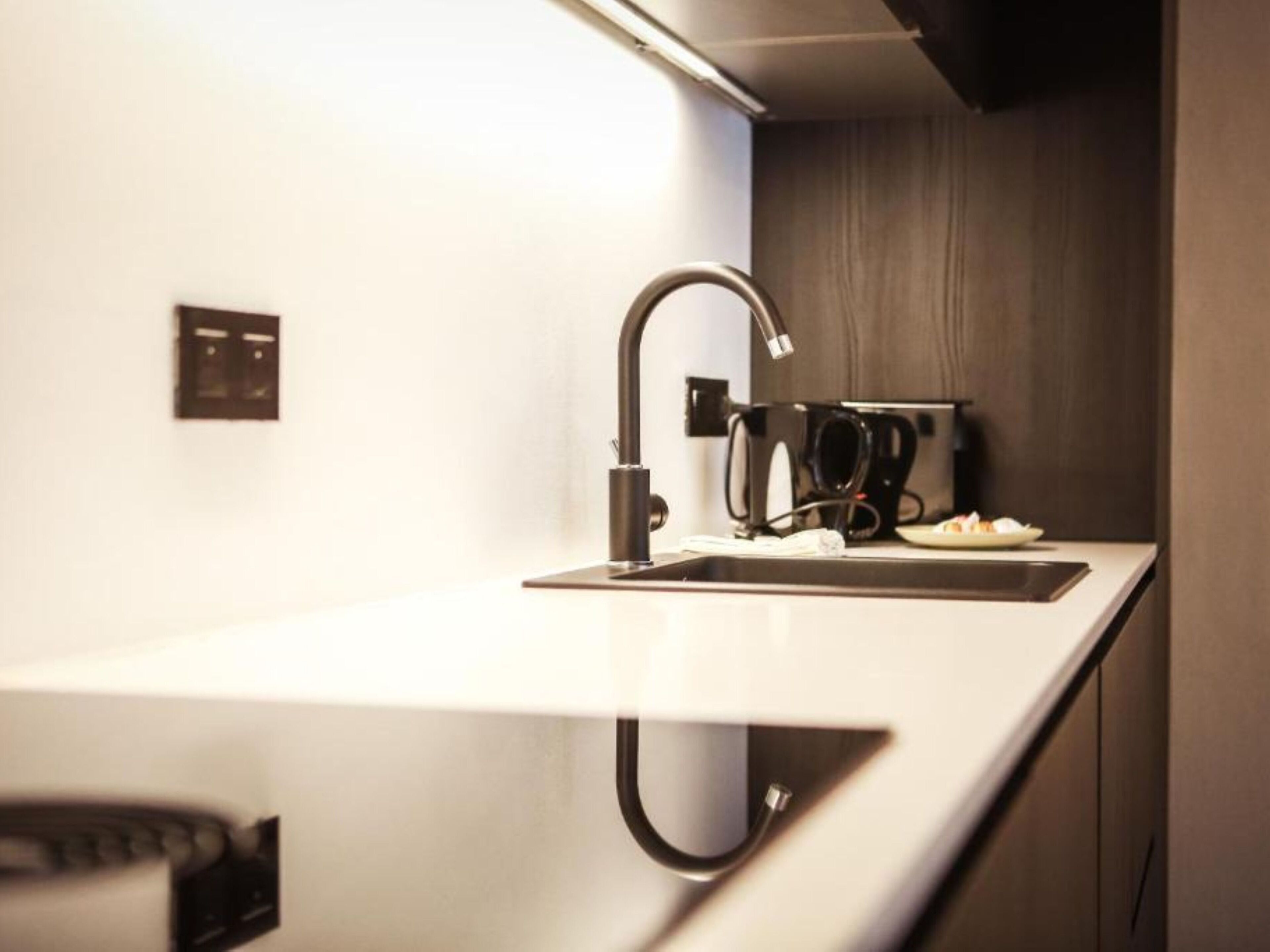 Una cocina moderna con un grifo negro elegante, una encimera blanca y una cafetera.