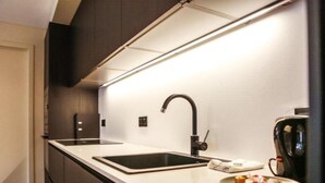 Une cuisine moderne avec un robinet noir, un plan de travail blanc et une machine à café.