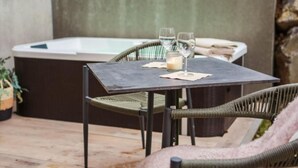 Un espace patio aménagé avec une table, deux chaises, une bougie et un jacuzzi.