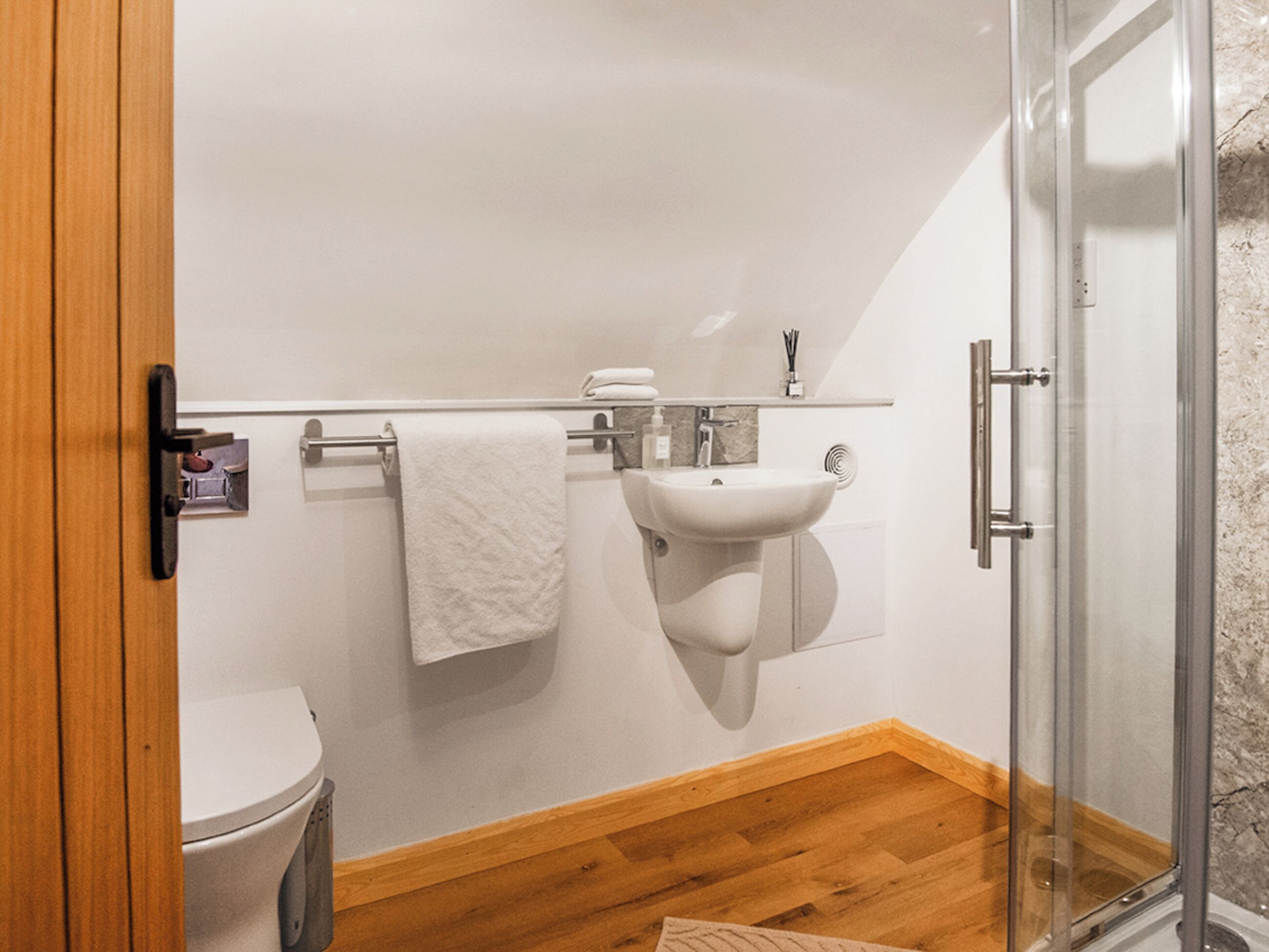 Un baño con inodoro, lavamanos y cabina de ducha de vidrio.
