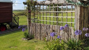 A rustic wooden gate with a wooden fence and a wooden structure with a metal roof in the background.