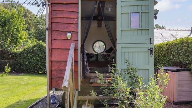 A rustic cabin with a green door, a small porch, and a window.