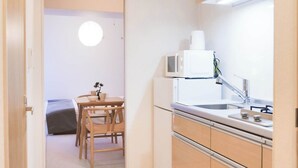 A modern kitchen with wooden cabinets, a stainless steel sink, and a dining area with a table and chairs.