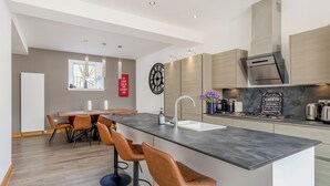 Eine moderne Küche mit einer zentralen Kochinsel, Barhocker und einem Essbereich mit Tisch und Stühlen.