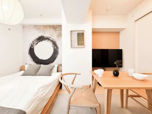 A modern bedroom with a bed, bedside table, and a wall-mounted TV. - Triphome Otsuka Sugamo 2025 New 7 mins 2 stations (Toshima City)