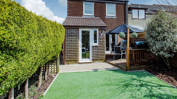 Une maison à deux étages avec un patio, une clôture en bois et une pelouse bien entretenue.