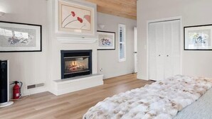 Un salon moderne avec une cheminée, un plancher en bois et un plaid en fourrure.