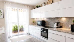 Eine moderne Küche mit weißen Schränken, Granit Arbeitsplatten, einem schwarzen Backofen und einer Kaffeemaschine.